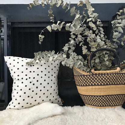Handcrafted African mudcloth pillow in minimalist white for modern homes. Black and white seen here with African basket and sheepskin rugs.