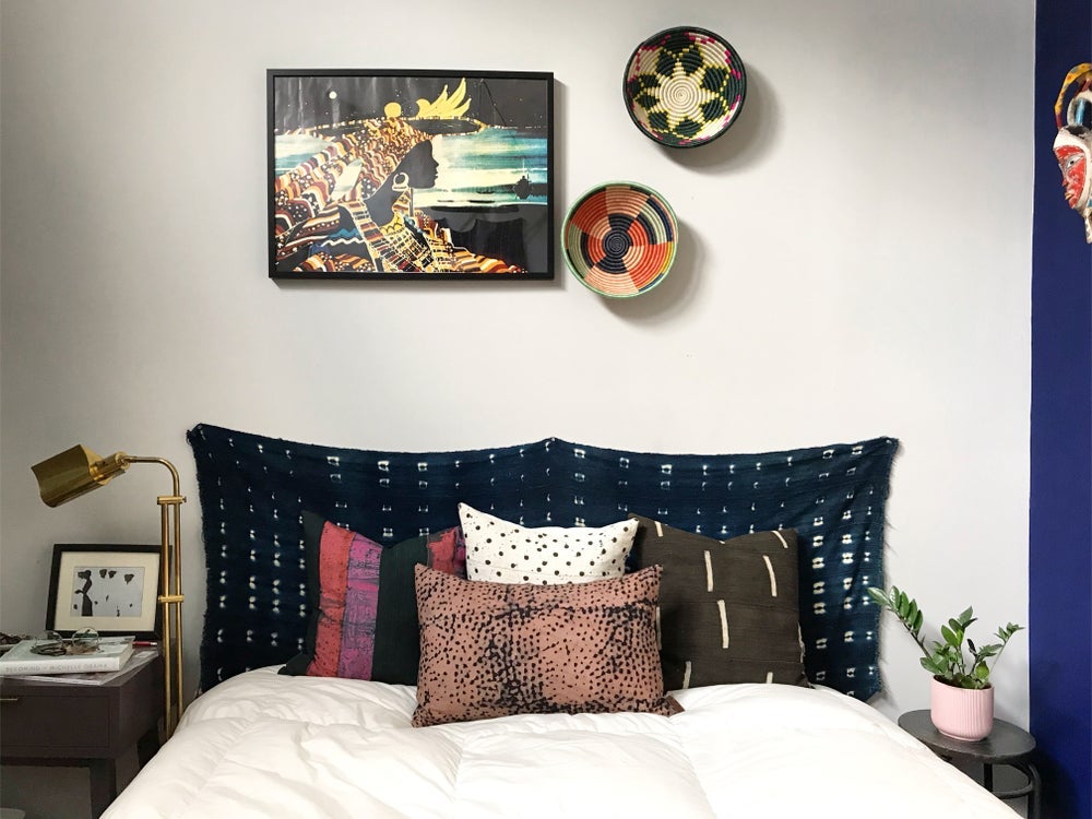 Handcrafted African mudcloth pillow in minimalist white for modern homes. Black and white seen here with African baskets and art in eclectic bedroom.